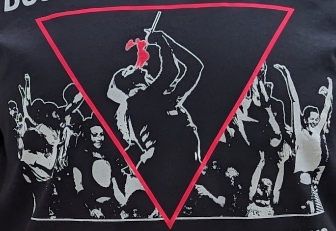 part of a t-shirt with the design of a fat fire eater set in an inverted pink triangle with a crowd in white ink around them